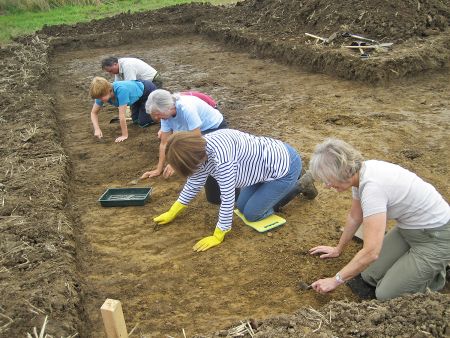 Volunteers work with trowels at an archaeological site.