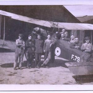 Black and whte photograph of airmen standing in front of a biplane.