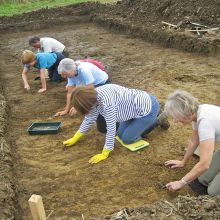 Volunteers work with trowels at an archaeological site.